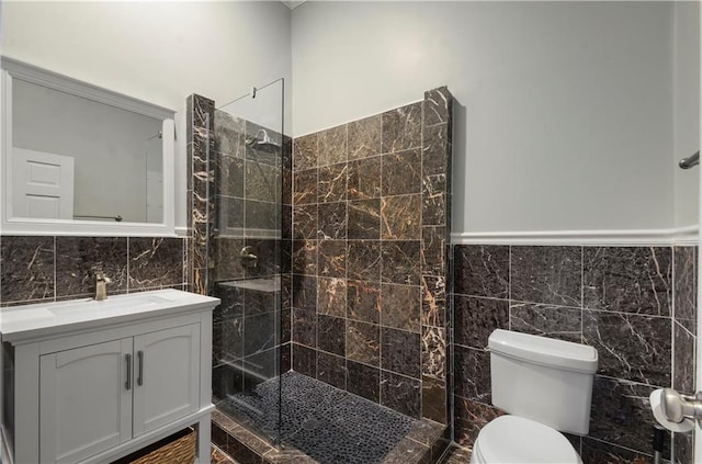 bathroom with vanity, toilet, tile walls, and a tile shower