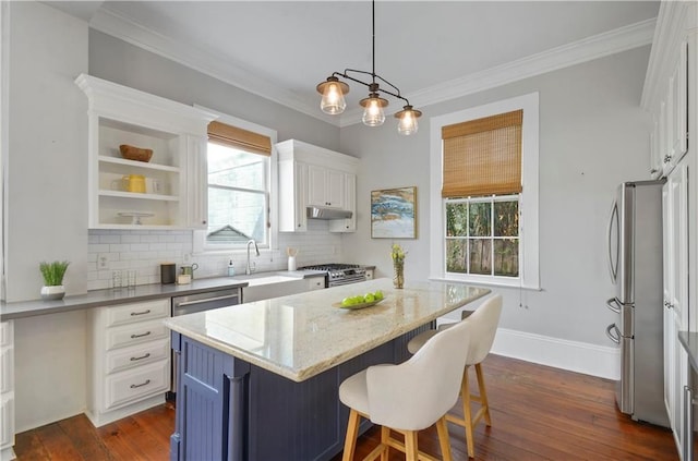 kitchen with pendant lighting, a kitchen island, dark hardwood / wood-style flooring, white cabinetry, and stainless steel appliances