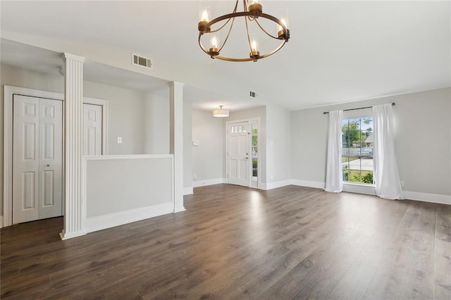 empty room with a chandelier, ornate columns, and dark wood-type flooring