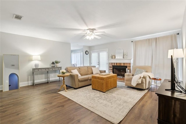 living room with ceiling fan, dark hardwood / wood-style flooring, and a brick fireplace