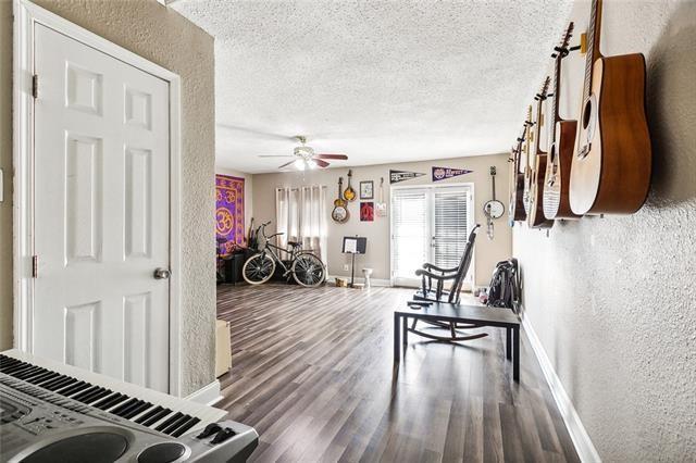 living room featuring hardwood / wood-style flooring, ceiling fan, and a textured ceiling