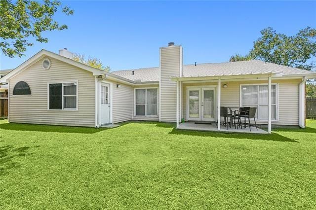 rear view of house featuring a patio area, a yard, and french doors