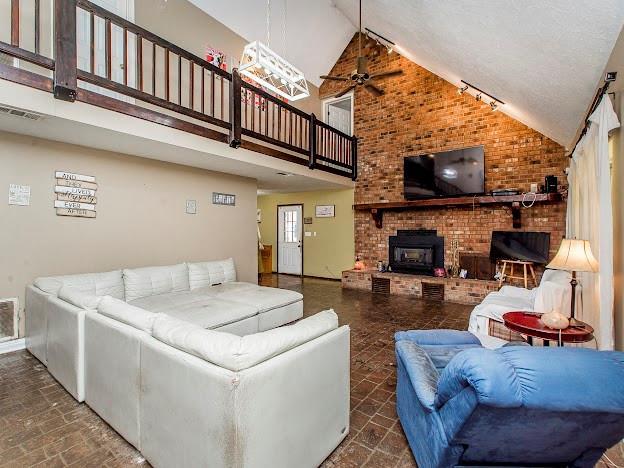 living room featuring a wood stove, track lighting, high vaulted ceiling, and ceiling fan