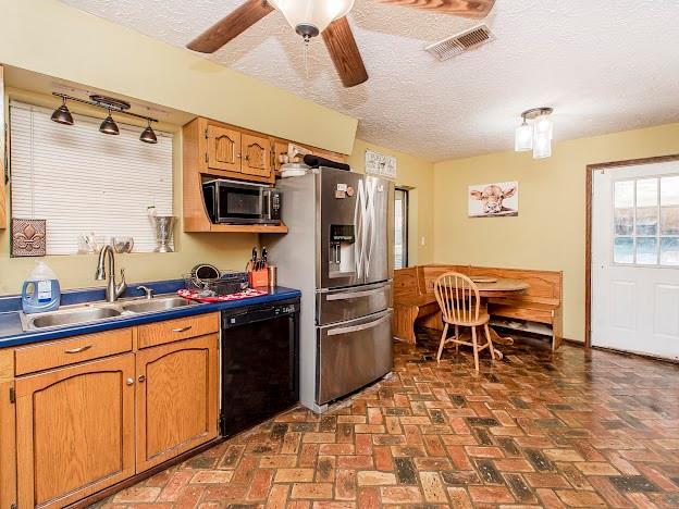 kitchen with a textured ceiling, stainless steel appliances, ceiling fan, and sink