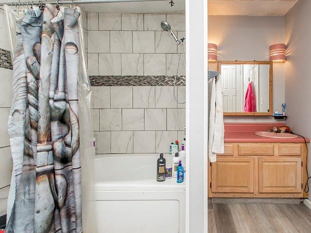 bathroom with vanity, hardwood / wood-style flooring, and shower / bath combo with shower curtain