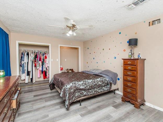 bedroom featuring a textured ceiling, ceiling fan, light hardwood / wood-style flooring, and a closet