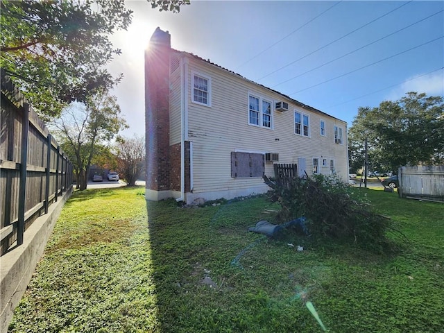 back of house featuring a lawn, a chimney, and fence