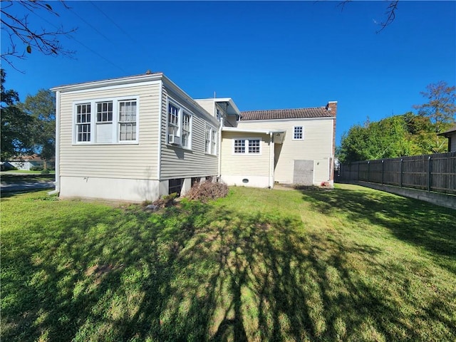 rear view of property featuring a chimney, a yard, and fence