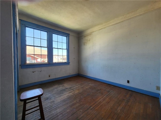 empty room featuring baseboards and hardwood / wood-style flooring