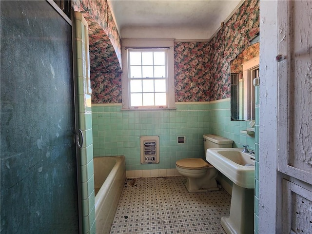 bathroom featuring toilet, a shower with door, heating unit, wainscoting, and wallpapered walls