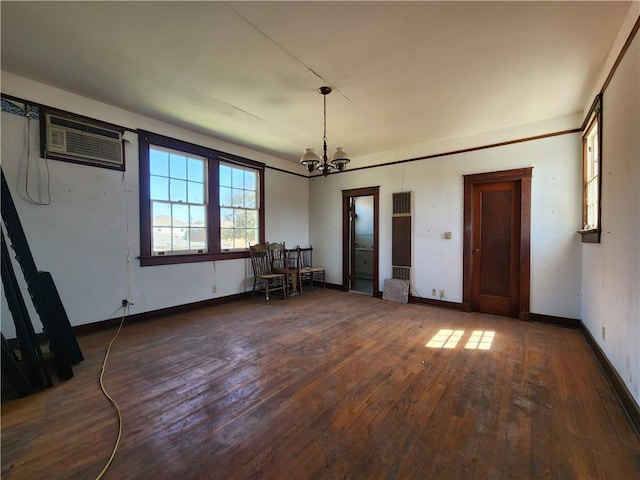 empty room with hardwood / wood-style flooring, a notable chandelier, baseboards, and a wall mounted AC