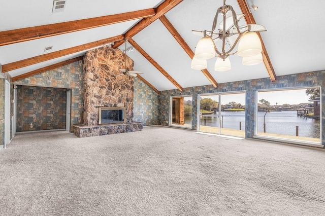 unfurnished living room with beam ceiling, a stone fireplace, carpet floors, and a water view