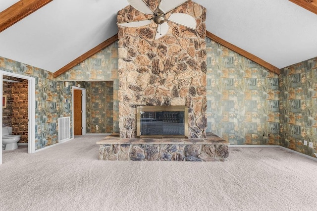 unfurnished living room with ceiling fan, beamed ceiling, high vaulted ceiling, carpet floors, and a fireplace