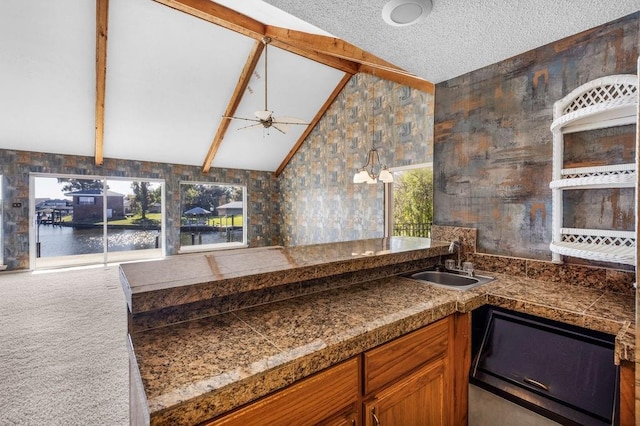 kitchen with a water view, sink, vaulted ceiling with beams, ceiling fan, and carpet floors