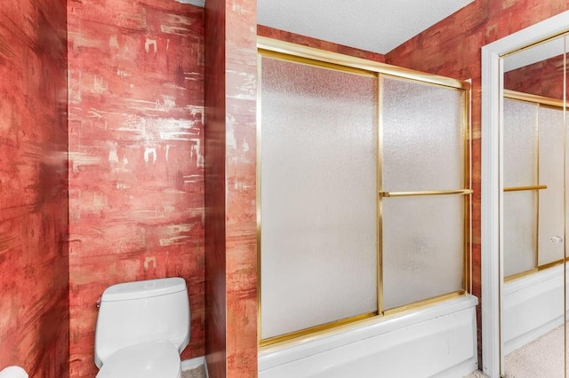 bathroom with combined bath / shower with glass door and toilet