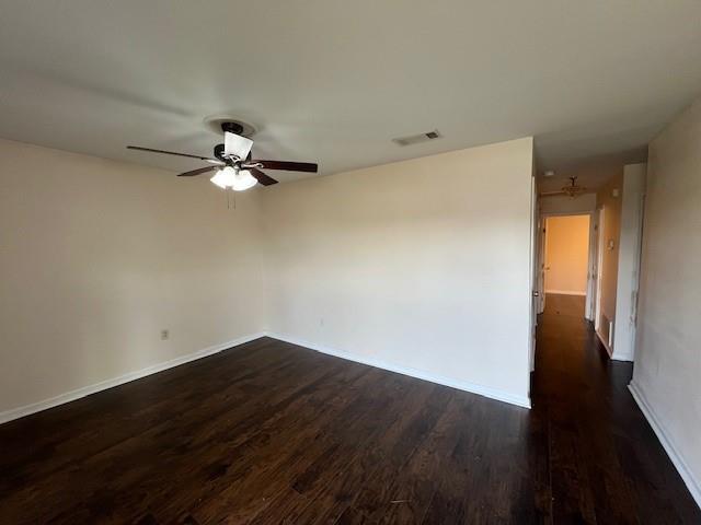 empty room with ceiling fan and dark hardwood / wood-style flooring