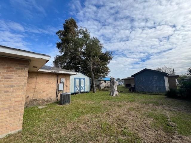 view of yard featuring a storage shed and central AC