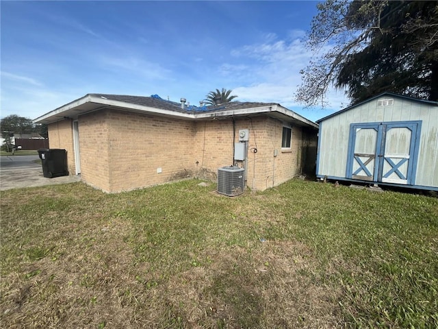 back of property with a storage unit, a yard, and central air condition unit