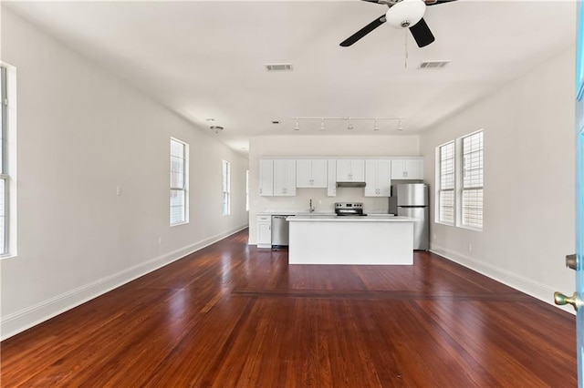 kitchen with dark hardwood / wood-style floors, a kitchen island, white cabinetry, and stainless steel appliances