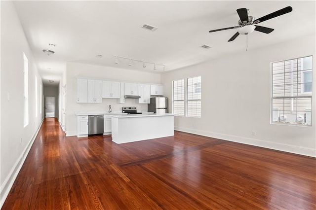 kitchen featuring ceiling fan, a center island, dark wood-type flooring, stainless steel appliances, and white cabinets