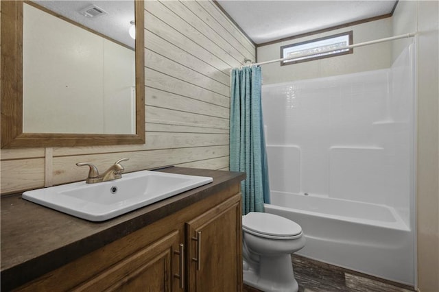 full bathroom featuring vanity, a textured ceiling, shower / tub combo with curtain, wooden walls, and toilet