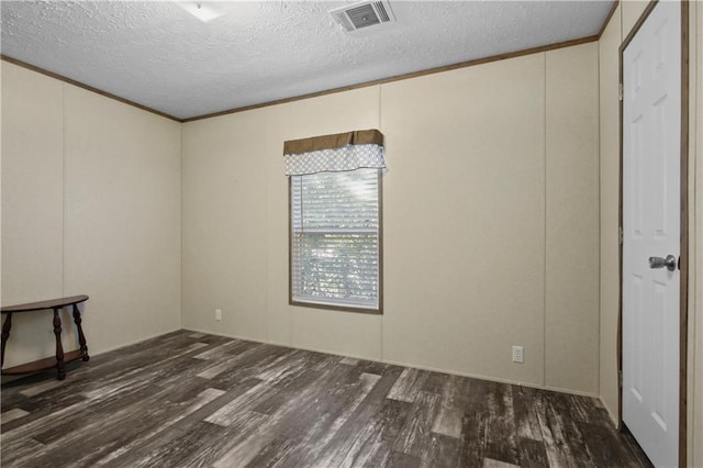 empty room featuring dark hardwood / wood-style flooring, a textured ceiling, and ornamental molding