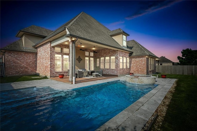 back house at dusk with a pool with hot tub, a patio area, ceiling fan, and an outdoor living space