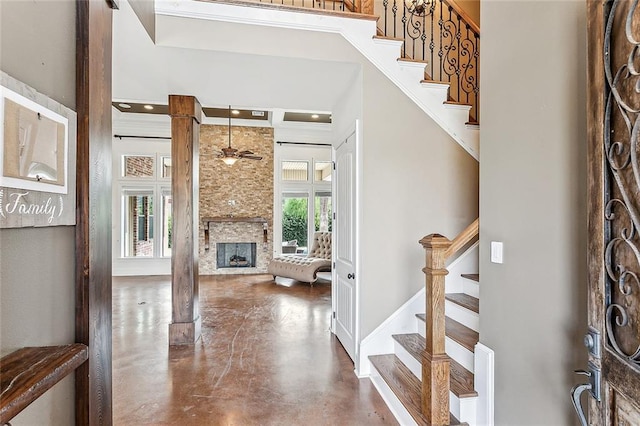 entryway with a towering ceiling, a fireplace, concrete floors, and ceiling fan