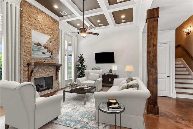 living room featuring beamed ceiling, ornamental molding, ceiling fan, coffered ceiling, and a stone fireplace