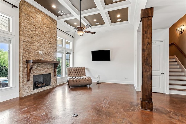 unfurnished room with coffered ceiling, crown molding, ceiling fan, a fireplace, and beam ceiling