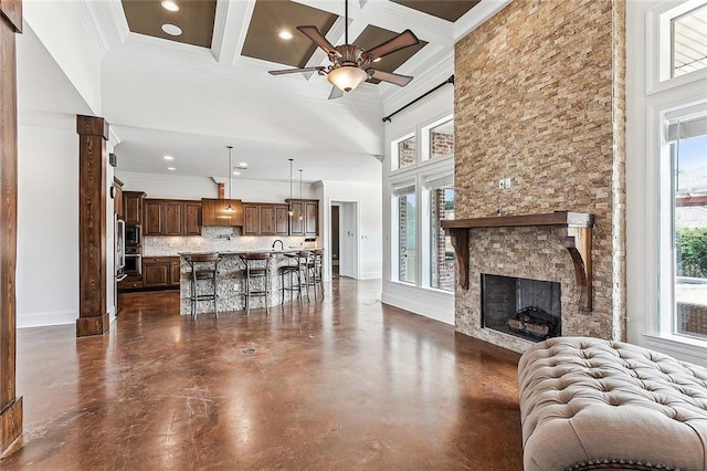 living room with beam ceiling, coffered ceiling, crown molding, and a fireplace