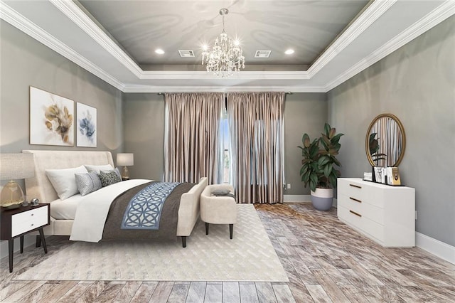 bedroom featuring a notable chandelier, light wood-type flooring, ornamental molding, and a tray ceiling