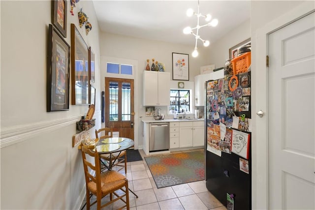 kitchen featuring black refrigerator, stainless steel dishwasher, sink, white cabinetry, and light tile patterned flooring