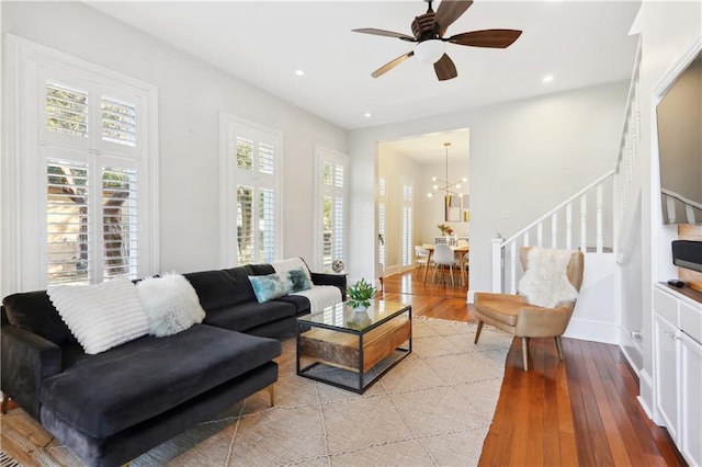 living room with ceiling fan with notable chandelier and light hardwood / wood-style floors