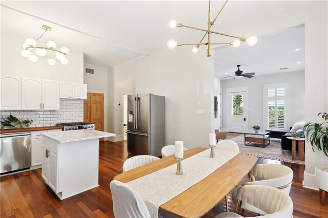 dining room featuring ceiling fan with notable chandelier and dark wood-type flooring