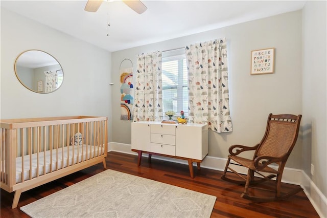 bedroom featuring dark hardwood / wood-style floors, ceiling fan, and a nursery area