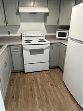 kitchen featuring gray cabinets, white appliances, and dark wood-type flooring