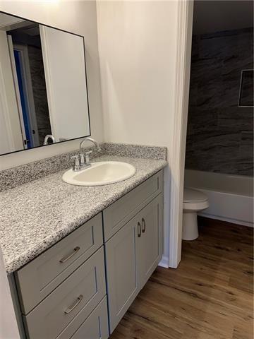 bathroom featuring wood-type flooring, vanity, and toilet