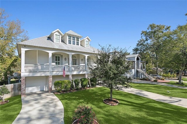 view of front facade with metal roof, covered porch, concrete driveway, stairway, and a front lawn