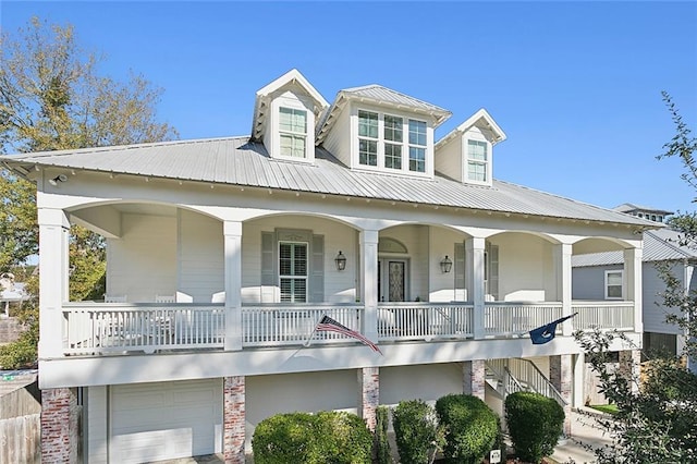 view of front of property with a garage, covered porch, metal roof, and stairway