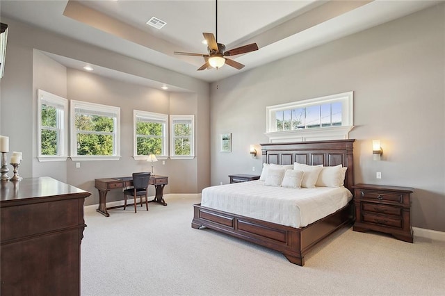 carpeted bedroom with a raised ceiling and ceiling fan