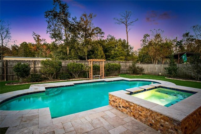 pool at dusk with an in ground hot tub and a patio area