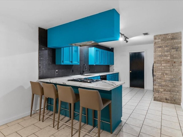 kitchen with sink, blue cabinets, kitchen peninsula, a breakfast bar area, and decorative backsplash