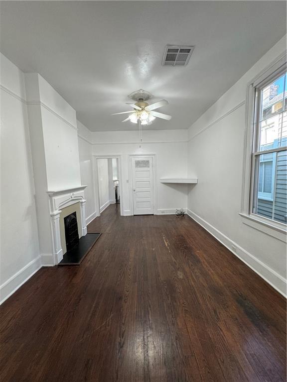 unfurnished living room with ceiling fan and dark wood-type flooring