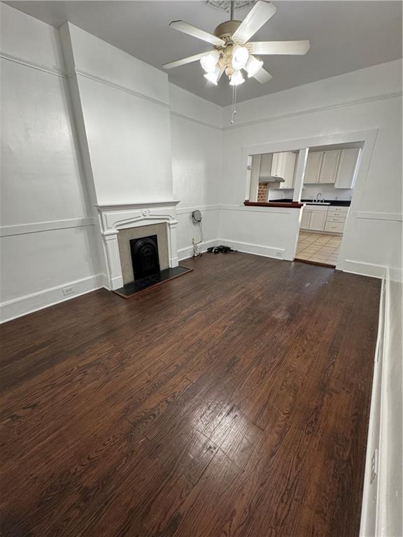 unfurnished living room featuring ceiling fan and dark hardwood / wood-style flooring