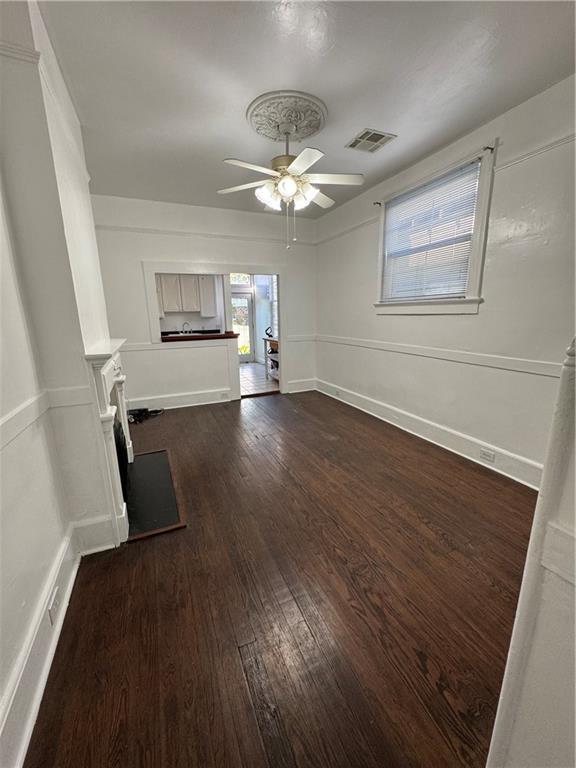 unfurnished living room featuring ceiling fan and dark wood-type flooring