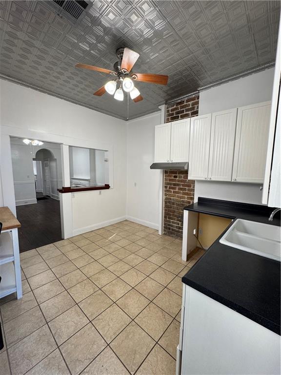 kitchen featuring white cabinetry, sink, ceiling fan, light tile patterned floors, and ornamental molding