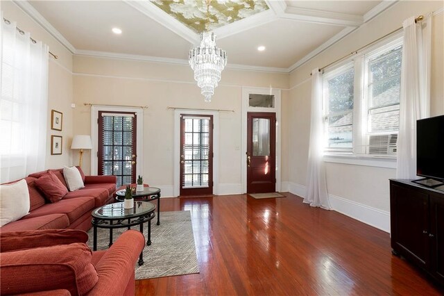 living room with wood-type flooring, crown molding, plenty of natural light, and a notable chandelier