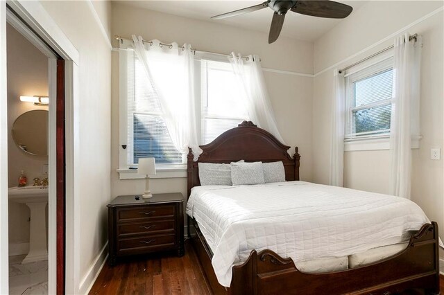 bedroom featuring dark hardwood / wood-style flooring, ensuite bathroom, and ceiling fan