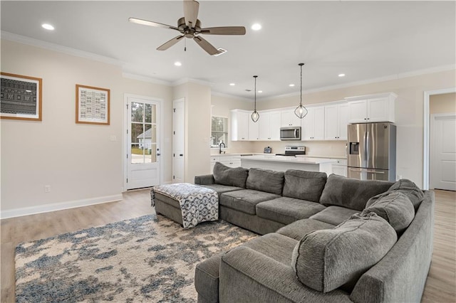 living room featuring ceiling fan, sink, light hardwood / wood-style floors, and ornamental molding